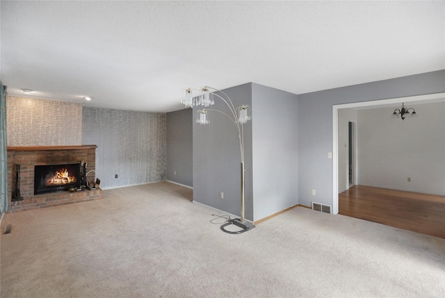 unfurnished living room featuring a fireplace, light carpet, and a notable chandelier