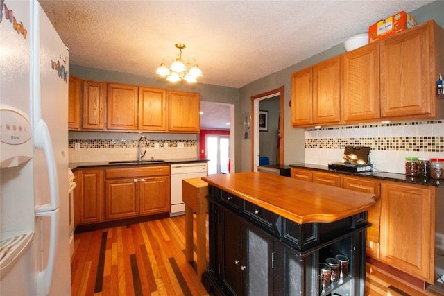 kitchen featuring white appliances, light hardwood / wood-style floors, a notable chandelier, sink, and tasteful backsplash