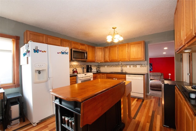 kitchen featuring sink, decorative light fixtures, an inviting chandelier, white appliances, and light wood-type flooring