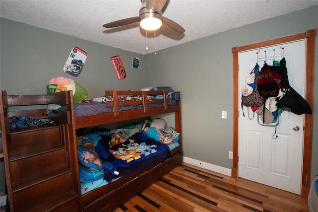 bedroom with ceiling fan, hardwood / wood-style floors, and a textured ceiling