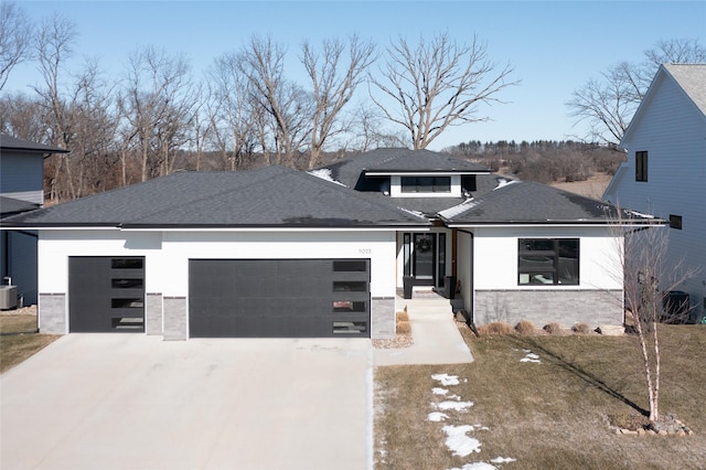 prairie-style home featuring central AC unit and a garage