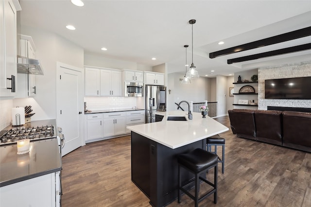 kitchen featuring appliances with stainless steel finishes, an island with sink, and white cabinets