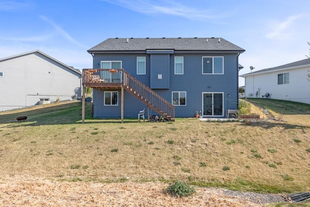 rear view of house with a wooden deck and a lawn