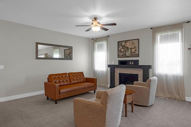 carpeted living room with a tiled fireplace and ceiling fan