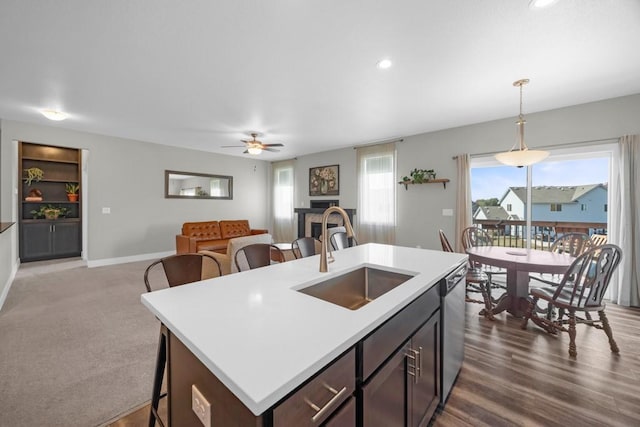 kitchen with sink, ceiling fan, an island with sink, dark brown cabinetry, and pendant lighting