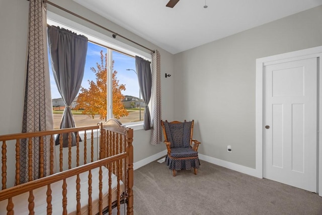 carpeted bedroom with ceiling fan and a crib