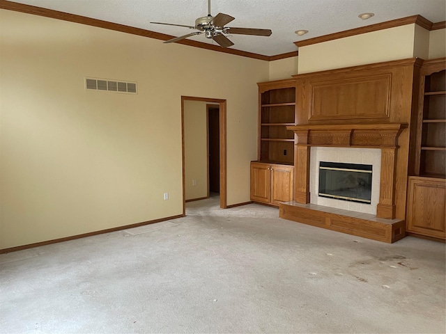 unfurnished living room featuring a textured ceiling, ceiling fan, a tiled fireplace, ornamental molding, and light carpet