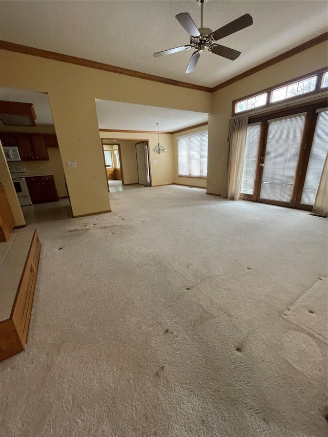 unfurnished living room featuring ceiling fan with notable chandelier, light carpet, and crown molding