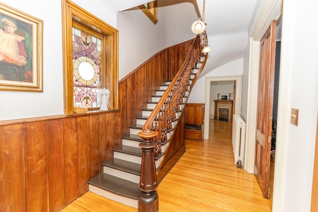 stairs featuring wood-type flooring, radiator heating unit, and ornamental molding