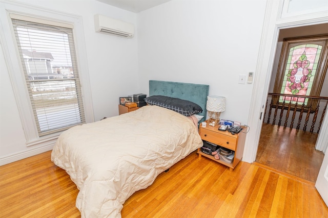 bedroom featuring an AC wall unit, multiple windows, and hardwood / wood-style flooring