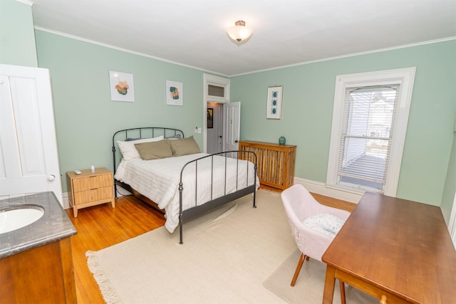 bedroom with sink, crown molding, and hardwood / wood-style flooring