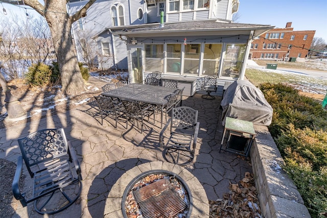 view of patio / terrace with an outdoor fire pit and a sunroom