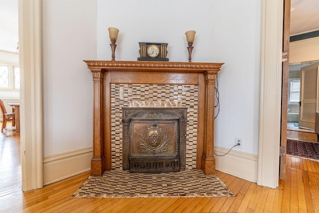 details with a tiled fireplace and wood-type flooring