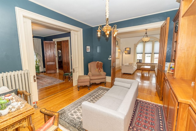 living area featuring an inviting chandelier, radiator heating unit, ornamental molding, and light hardwood / wood-style floors