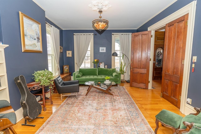 living area with ornamental molding, an inviting chandelier, and wood-type flooring