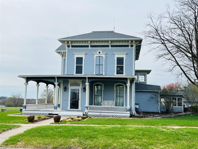italianate-style house with a front yard, a porch, and a shingled roof