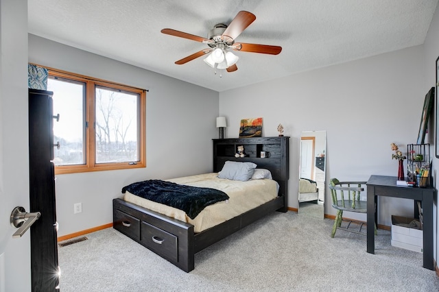 bedroom with carpet floors, ceiling fan, and a textured ceiling