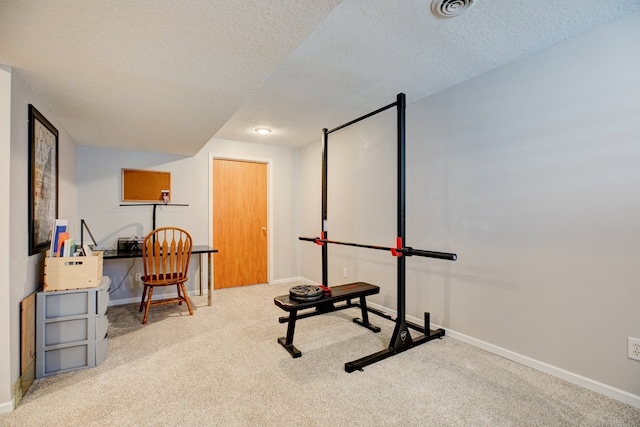 exercise area with a textured ceiling and light colored carpet