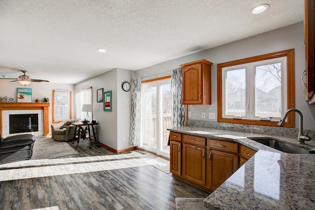 kitchen with sink, a textured ceiling, light stone counters, ceiling fan, and dark hardwood / wood-style flooring