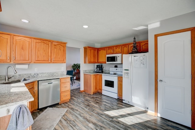 kitchen featuring white appliances, light stone counters, dark hardwood / wood-style flooring, and sink