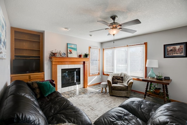 living room with a fireplace, a textured ceiling, ceiling fan, and hardwood / wood-style floors