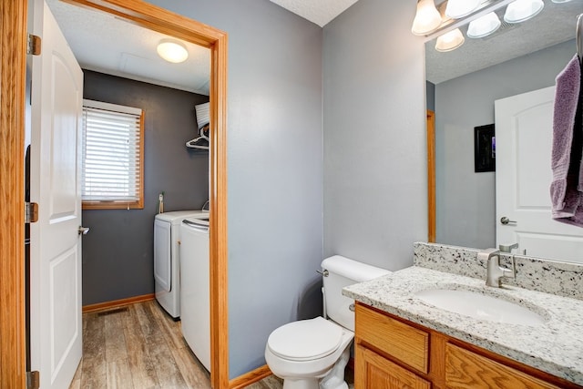 bathroom with toilet, vanity, hardwood / wood-style flooring, a textured ceiling, and washing machine and clothes dryer