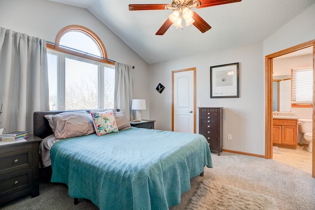 carpeted bedroom featuring vaulted ceiling, ensuite bath, ceiling fan, and multiple windows