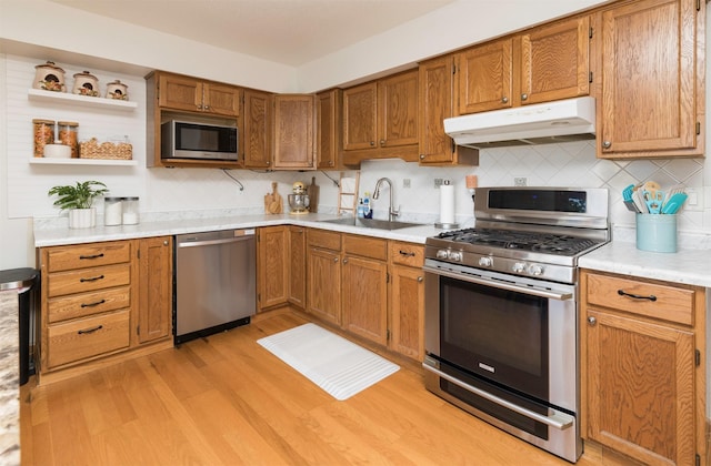 kitchen with sink, tasteful backsplash, light hardwood / wood-style flooring, and appliances with stainless steel finishes