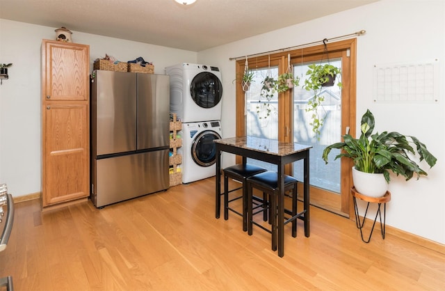 dining area with stacked washer and clothes dryer and light wood-type flooring