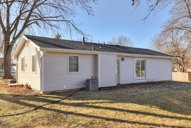 rear view of house with central AC and a yard