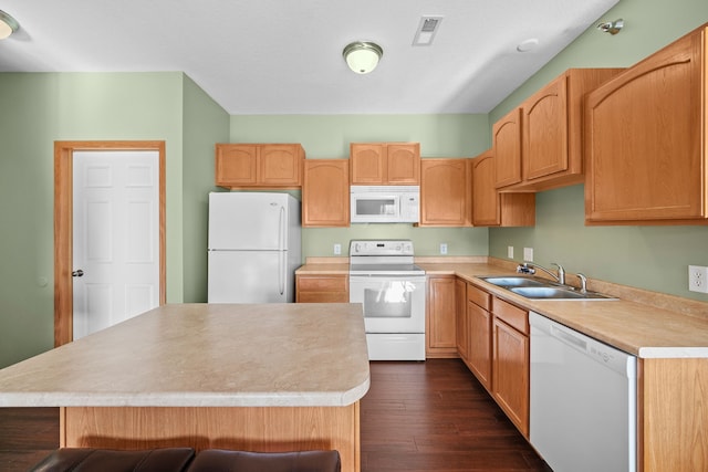 kitchen featuring sink, a center island, white appliances, a kitchen bar, and dark hardwood / wood-style flooring