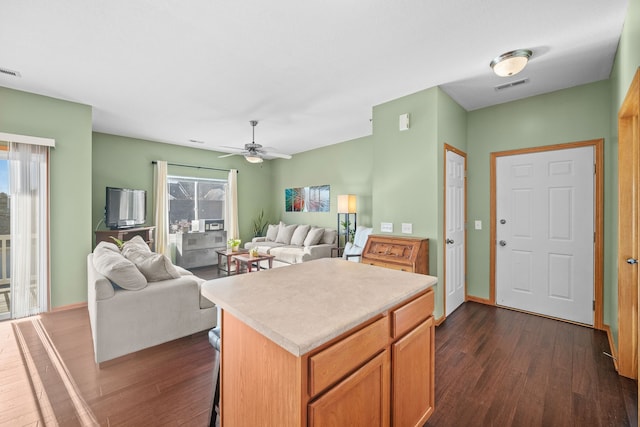 kitchen featuring dark hardwood / wood-style flooring, a center island, ceiling fan, and a breakfast bar