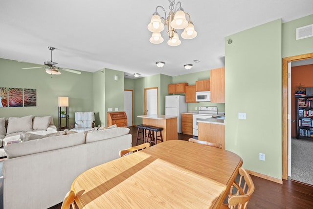 dining room featuring ceiling fan with notable chandelier and dark hardwood / wood-style flooring