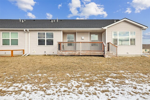 snow covered rear of property with a deck and a yard