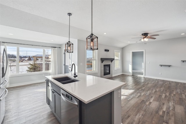 kitchen featuring a kitchen island with sink, pendant lighting, sink, stainless steel dishwasher, and lofted ceiling