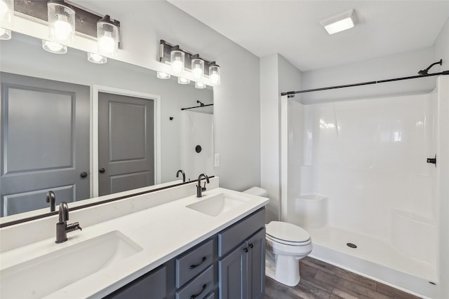 bathroom featuring toilet, wood-type flooring, vanity, and a shower