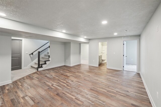 basement featuring a textured ceiling and light wood-type flooring