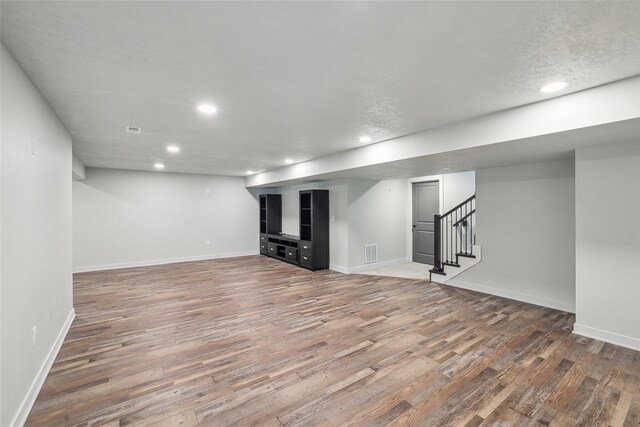 basement featuring hardwood / wood-style flooring and a textured ceiling