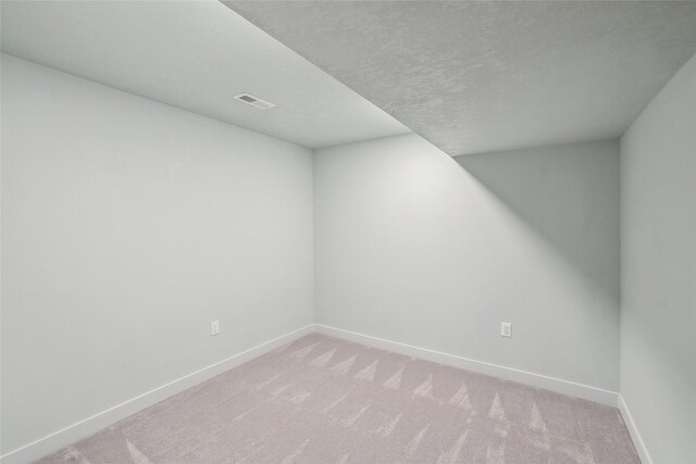 spare room featuring a textured ceiling and light carpet