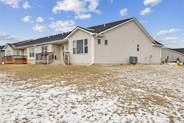 snow covered property with central AC and a wooden deck