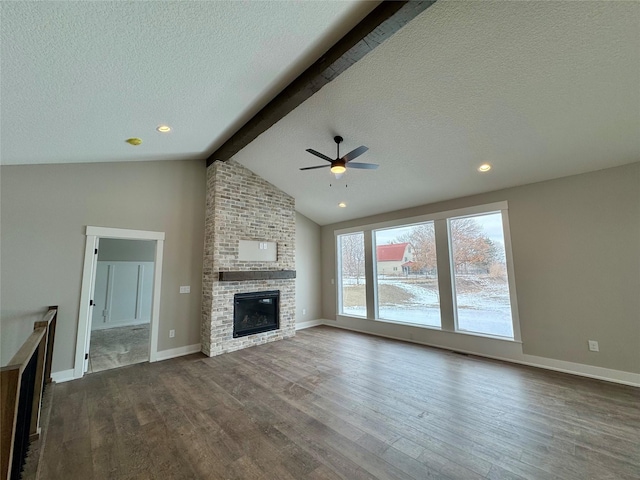 unfurnished living room with vaulted ceiling with beams, ceiling fan, dark hardwood / wood-style flooring, a brick fireplace, and a textured ceiling