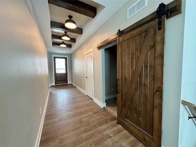 doorway to outside featuring hardwood / wood-style flooring, a barn door, and beam ceiling