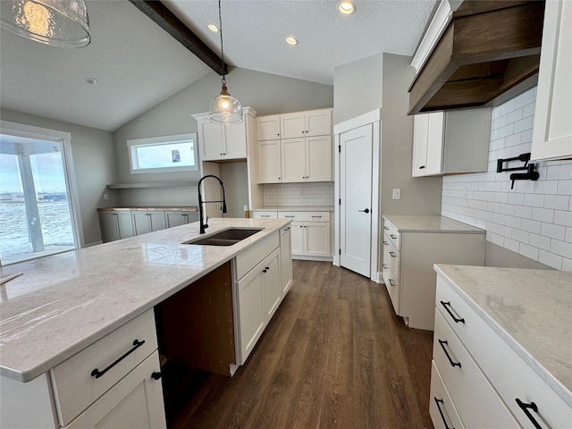 kitchen with dark wood-type flooring, lofted ceiling with beams, decorative light fixtures, white cabinets, and sink