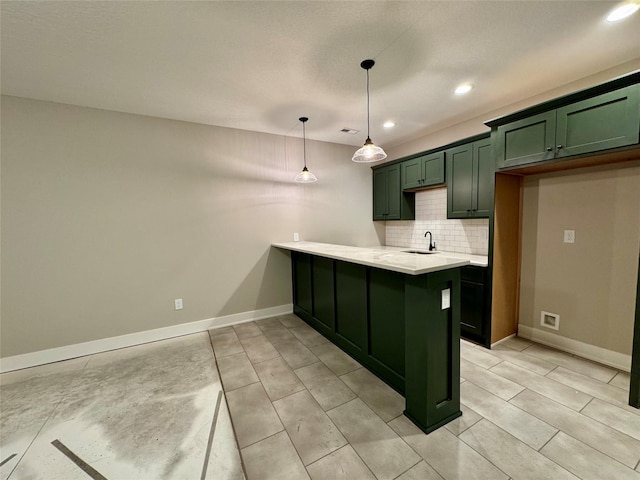 kitchen with sink, green cabinetry, tasteful backsplash, kitchen peninsula, and hanging light fixtures