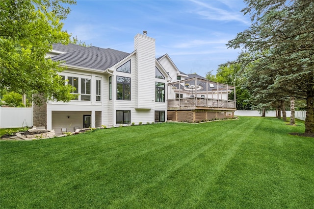 rear view of house featuring a deck and a yard