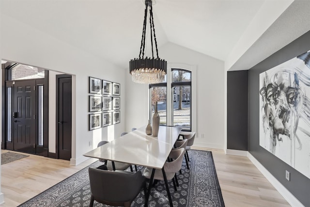 dining room featuring lofted ceiling, a chandelier, and light hardwood / wood-style floors