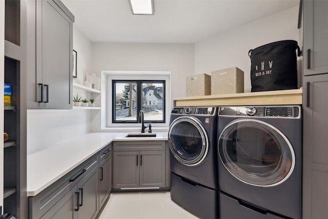 clothes washing area featuring sink, cabinets, and washing machine and clothes dryer