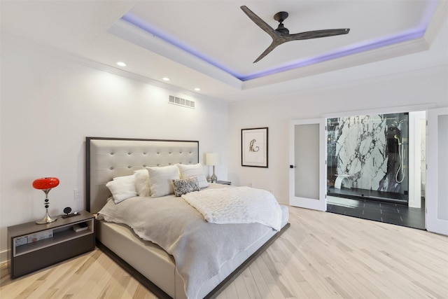 bedroom with a raised ceiling, ceiling fan, and wood-type flooring