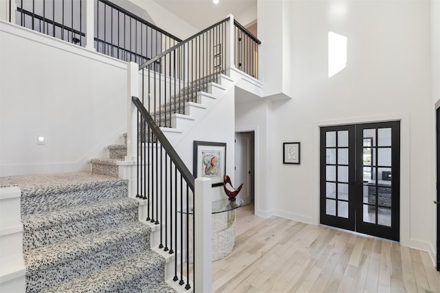 entrance foyer with french doors, a high ceiling, and light hardwood / wood-style floors