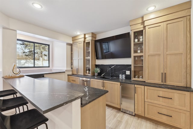 kitchen featuring sink, a kitchen breakfast bar, light hardwood / wood-style flooring, light brown cabinetry, and backsplash